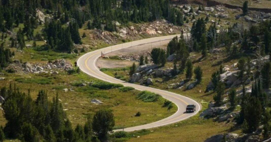 Vista aérea de la Carretera Beartooth serpenteando entre montañas con nieve en Montana, Estados Unidos.